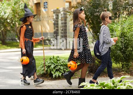 Gruppo di amici in costumi di Halloween camminando lungo la strada vogliono delle delizie Foto Stock