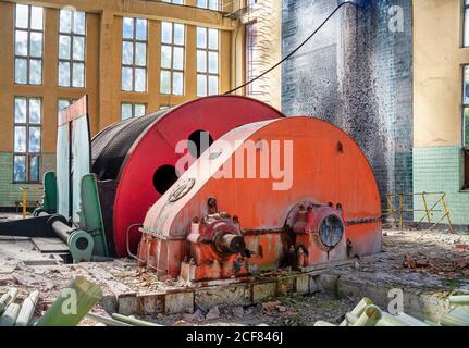 Macchina circolare industriale con meccanismo metallico che si trova all'interno deserted senza proprietà laboratorio industriale dilatato con pareti leggere e grandi finestre ad arco Foto Stock