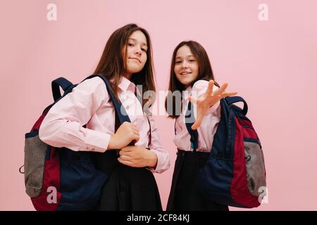 Ragazze gemelle dall'aspetto cool che posano con i loro zaini. Angolo basso Foto Stock