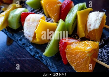 Kebab di frutta fatto di arance, fragole, Kiwi, Mango. Primo piano della macro. Messa a fuoco selettiva Foto Stock