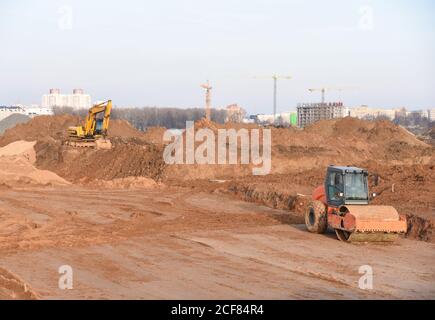 Vibrazione del rullo per la circolazione su strada monocilindrico e dell'escavatore in cantiere. Attrezzature pesanti per lavori su strada e a terra. Scavo fondazione e posa su Foto Stock