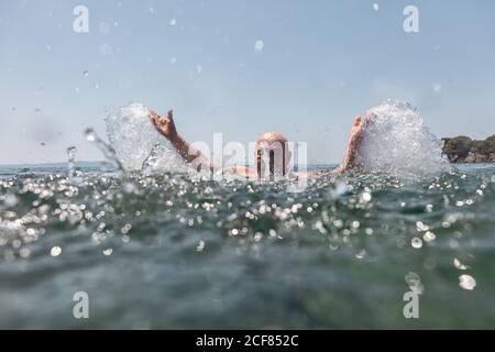 Baffi calvo uomo anziano godendo e spruzzi d'acqua in luminoso Giornata di sole in Grecia Halkidiki Foto Stock