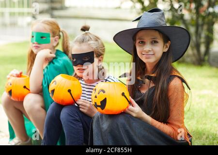Ritratto di amici felici in costumi con zucche sorridenti Fotocamera all'aperto durante la festa di Halloween Foto Stock
