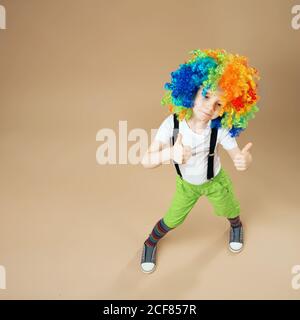 Bambini blitesome. Buon ragazzo clown con grande parrucca colorata. Piccolo  ragazzo in parrucca clown ballare e divertirsi. Ritratto a lunghezza intera  del ragazzo di compleanno Foto stock - Alamy
