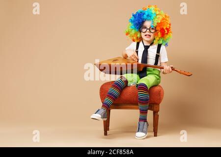 Bambini blitesome. Happy clown boy in grande wig color neon