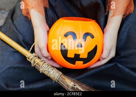 Primo piano di bambina seduta e tenendo in mano la zucca giocattolo per tratta nelle sue mani Foto Stock