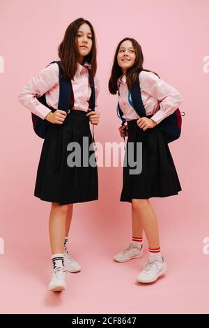 Felici le ragazze gemelle che posano con i loro zaini. Angolo basso Foto Stock