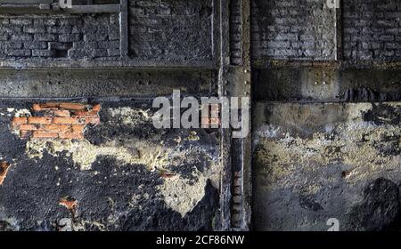 Muro di mattoni grugnosi con intonaco sporco sbriciolato situato all'interno invecchiato impianto industriale abbandonato Foto Stock