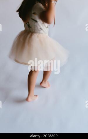 Vista posteriore ad alto angolo di un bambino attivo che indossa la gonna tutu ballare su sfondo bianco mentre ci si diverte in studio Foto Stock