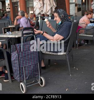 Belgrado, Serbia, 31 agosto 2020: Anziana donna seduta in un caffè, mangiando gelato e gesturando con la mano Foto Stock