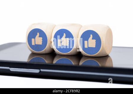 Tre semplici dadi con Facebook come icone che si stendano su uno schermo moderno smartphone. Concetto di coinvolgimento dei social media, paura di perdere, dipendenza Foto Stock