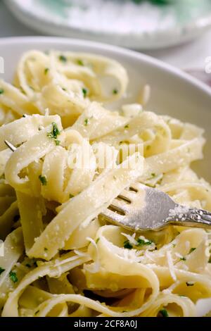 Tagliatelle cotte con salsa al pesto sulla forchetta Foto Stock