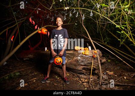 Ritratto di un ragazzo africano che guarda la macchina fotografica mentre visita il Festa di Halloween al buio all'aperto Foto Stock