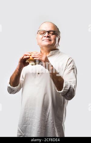 Indian Old Man mangiare hamburger o hamburger con succo di mango o bevanda fredda Foto Stock