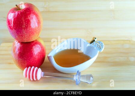 Festa ebraica di Rosh Hashana sfondo con miele e Apple su un tavolo di legno. Durante l'anno Ebraico Rosh Hashanah consuetudine mangiare le mele a fette immerso nel miele dolce simbolo del nuovo anno. Foto Stock