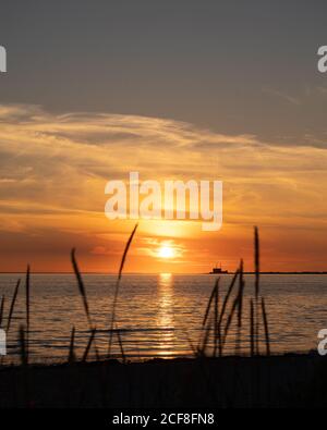 Tramonto sul mare con la silhouette della centrale nucleare di Barsebäck Visibile all'orizzonte in Svezia Foto Stock