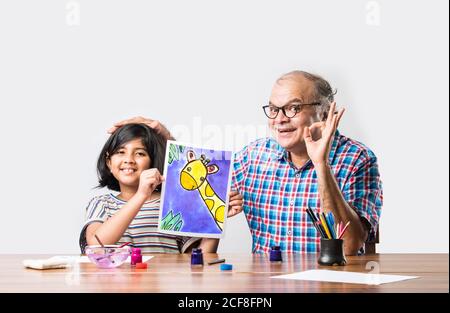 Buon nonno indiano e piccola nipote pittura con pennello e colori dell'acqua. Bambini art. Tempo libero con il nipote Foto Stock