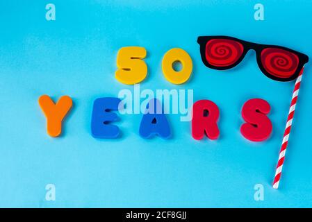 50 anni festeggiando il logo classico. Colorato felice anniversario 50 ° numeri colorati su sfondo blu. Saluti celebra la scheda. Cifre tradizionali di età. Posa piatta . Foto Stock