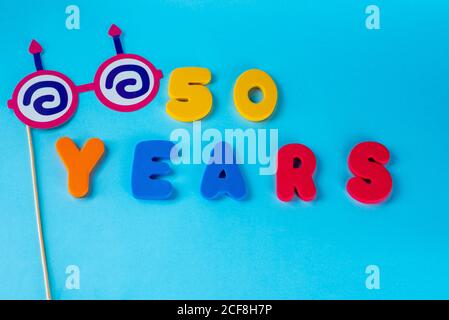 50 anni festeggiando il logo classico. Colorato felice anniversario 50 ° numeri colorati su sfondo blu. Saluti celebra la scheda. Cifre tradizionali di età. Vista dall'alto. Foto Stock