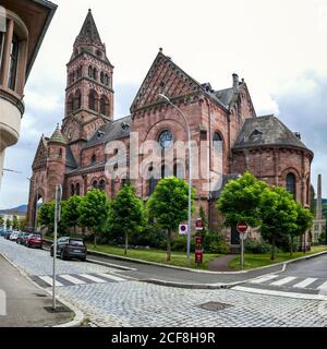 Grande chiesa in arenaria rossa con torre, ihe città vecchia di Munster, nei Vosgi montagne, Francia, Foto Stock