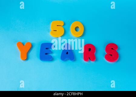 50 anni festeggiando il logo classico. Colorato felice anniversario 50 ° numeri colorati su sfondo blu. Saluti celebra la scheda. Cifre tradizionali di età. Posa piatta . Foto Stock