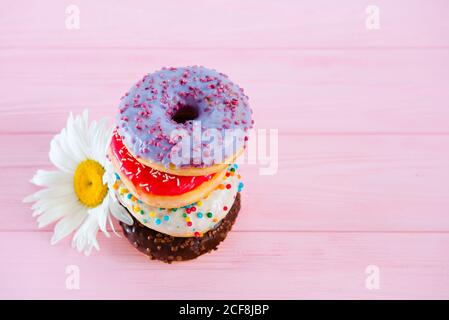 Set di ciambelle smaltate multicolore su sfondo rosa. Pasticceria dolce. Cibo spazzatura. Foto Stock