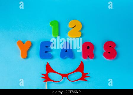 12 anni festeggiando il logo classico. Colorato felice anniversario 12 ° numeri carino su sfondo blu. Saluti celebra la scheda. Cifre tradizionali di età. Posa piatta . Foto Stock