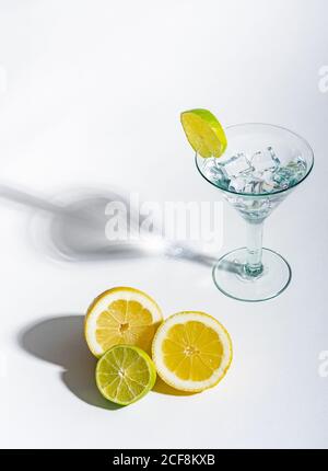 Bicchiere di bevanda pieno di cubetti di ghiaccio e arancia a fette lime e limone su sfondo bianco Foto Stock