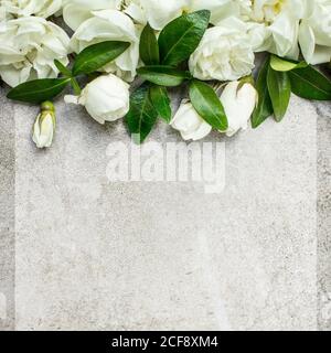 Matrimonio femminile, scena mock-up di articoli di cancelleria per compleanno. Biglietto d'auguri vuoto con bouquet di rose e foglie verdi. Fondo grigio cemento. Disposizione piatta, da a. Foto Stock