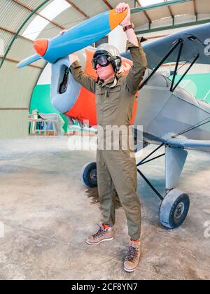 Pilota sicuro accanto al retro piano in hangar Foto Stock