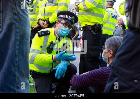 Un ufficiale di polizia parla con il protettore che blocca la strada durante la manifestazione della ribellione estinzione, Parliament Square, Londra, 1 settembre 2020 Foto Stock