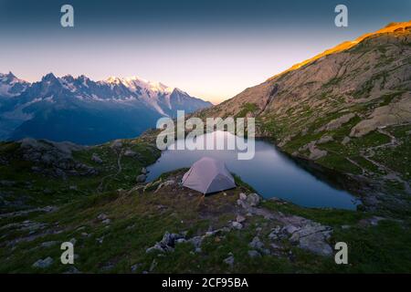 Lago di cristallo e tenda in montagne innevate alla luce del sole Foto Stock