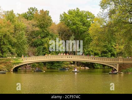 New York City, USA - 7 ottobre 2019: Il ponte di Bow in Central Park. Pipole che attraversa il ponte o che guarda al lago. Barche a remi sono sotto Foto Stock
