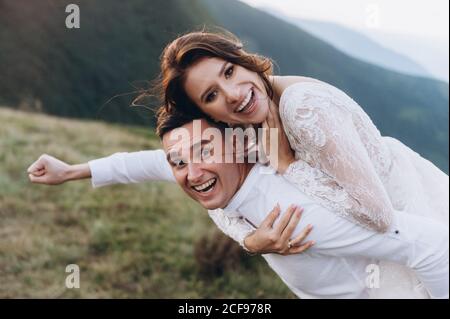 Sposi felici in pose divertenti sullo sfondo delle montagne. Foto Stock