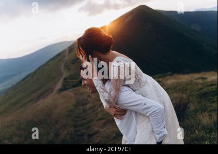 Felice appena sposato giovane coppia di nozze che festeggia e si divertono al tramonto bello nei mountans. Foto Stock