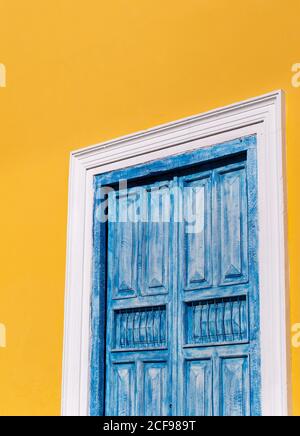 Finestra chiusa con persiane in legno blu araby su giallo brillante muro di edificio sotto il sole Foto Stock