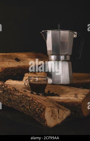 Tazza di caffè con bollitore e chicchi di caffè legna da ardere isolata su fondo nero Foto Stock