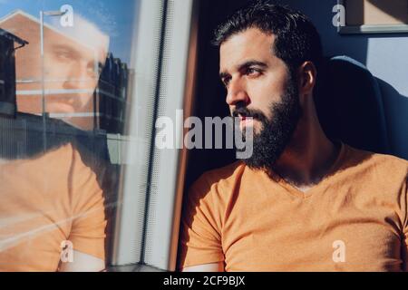 Uomo giovane e premuroso che guarda attraverso la finestra mentre si viaggia allenati Foto Stock