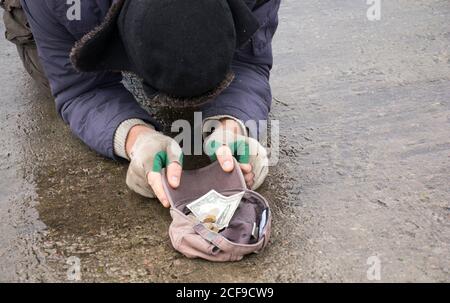 Il mendicante senza tetto chiede elemosina sul bridge.Beggar che mendica sulla strada.UN uomo senza tetto su una strada della città. Una persona senza casa. Foto Stock