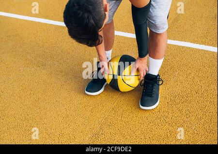 Gambe di raccolto giovane uomo e palla che gioca sul campo di pallacanestro all'aperto. Foto Stock