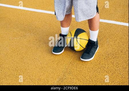 Gambe di raccolto giovane uomo e palla che gioca sul campo di pallacanestro all'aperto. Foto Stock