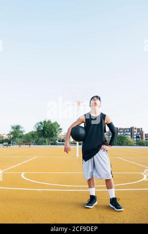 Giovane uomo che gioca sul campo di pallacanestro giallo all'aperto. Foto Stock