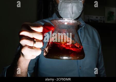 barista maschile anonimo indossare maschera protettiva durante la pandemia di covid 19 all'interno della caffetteria con macchina per caffè chemex Foto Stock