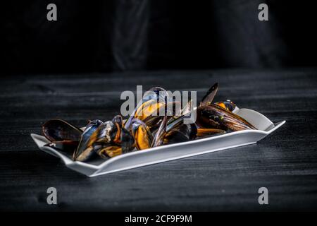 Cozze al vapore con salsa tailandese in piatto bianco Foto Stock