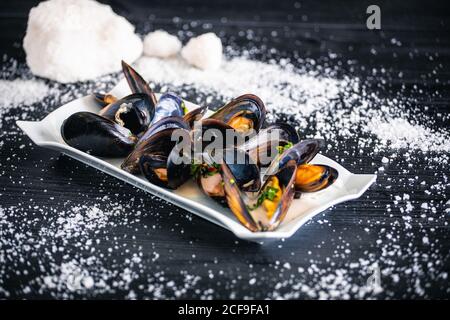 Cozze al vapore con salsa tailandese in piatto bianco Foto Stock