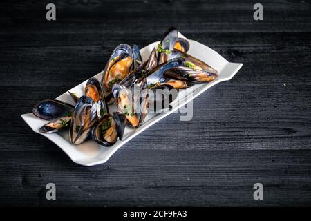 Cozze al vapore con salsa tailandese in piatto bianco Foto Stock