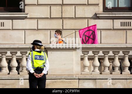 Un protettore con bandiera passa davanti a un ufficiale di polizia in una manifestazione della ribellione estinzione, Parliament Square, Londra, 2 settembre 2020 Foto Stock