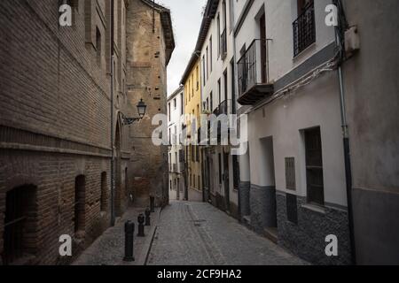 Antico vicolo acciottolato con un percorso in pietra a blocchi tra vecchi bricked Edifici ad Albaicin a Granada in Spagna Foto Stock