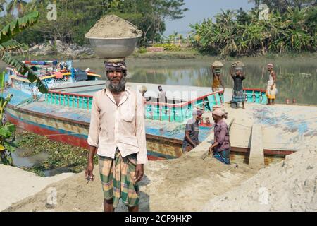 Etnie locali che scaricano pesce dalla barca dopo aver pescato Barisal in Bangladesh Foto Stock