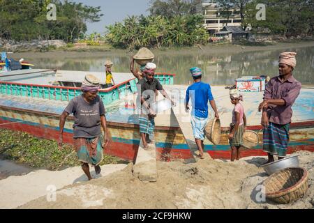 Etnie locali che scaricano pesce dalla barca dopo aver pescato Barisal in Bangladesh Foto Stock